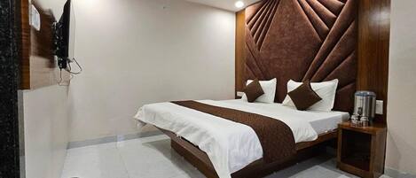 Una habitación de hotel moderna con una cama grande, un cabecero de madera y una mesita de noche pequeña.