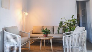 A room with a white wicker sofa, two white wicker chairs, a small wooden coffee table, and a potted plant. - Casa Camila · Private Cortijo with pool in Cabo de Gata (AN)