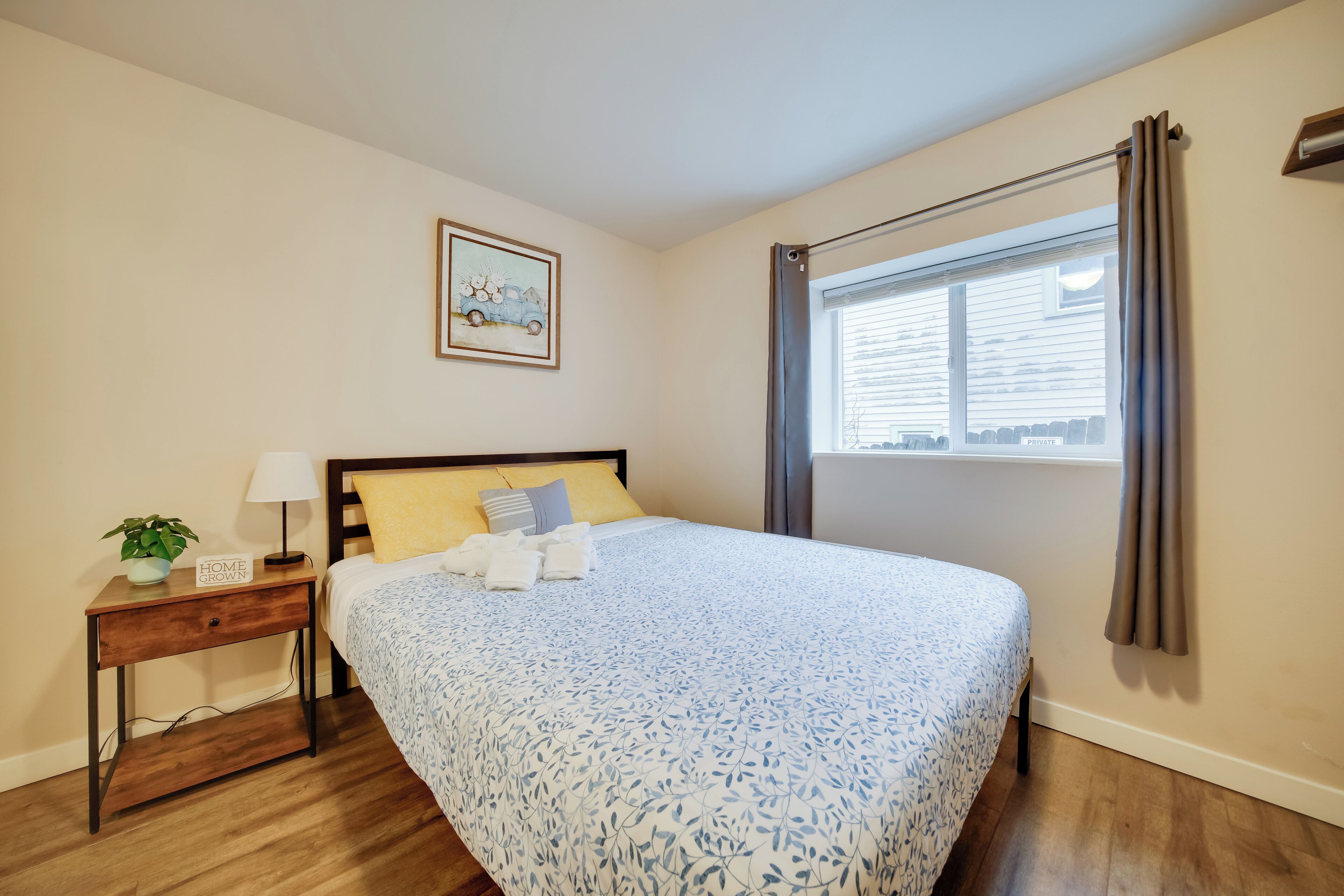 A neatly arranged bedroom with a bed, bedside table, lamp, and a window with curtains.