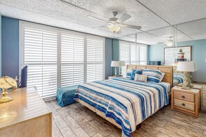 A bedroom with a large bed, two bedside tables, a desk, and a ceiling fan. - Beachfront 3BR w/ Pools, Hot Tubs & Sauna (South Padre Island)