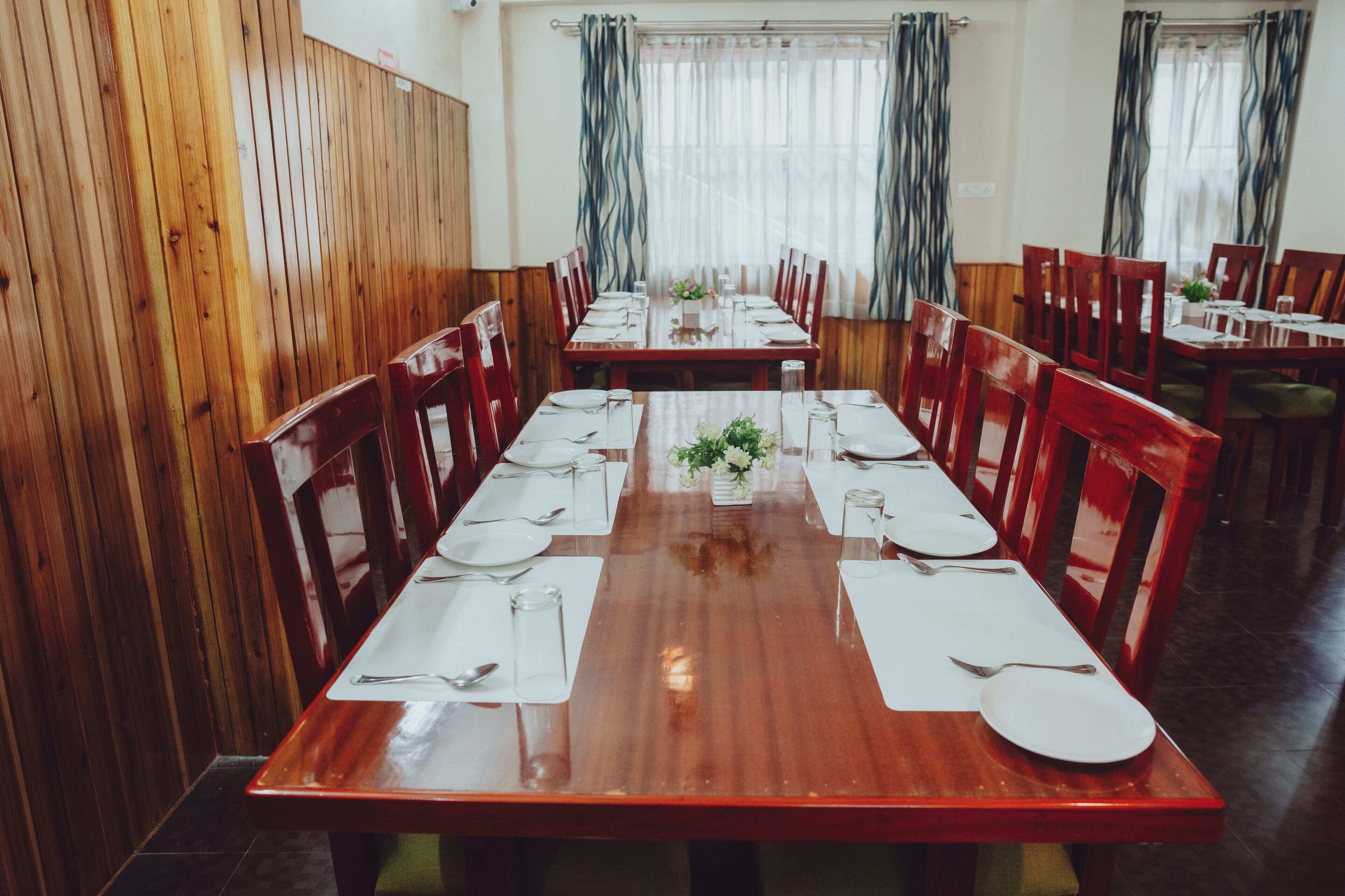 A dining area with wooden walls and tables set for multiple people.