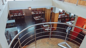 A multi-level restaurant with wooden paneling and a marble staircase. - Hotel Pride (Kalimpong)