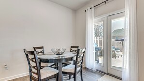A dining area with a round table, four chairs, and a decorative bowl centerpiece. - Near Atl! Spacious Townhome w/ Patio & WFH Setup (Douglasville)