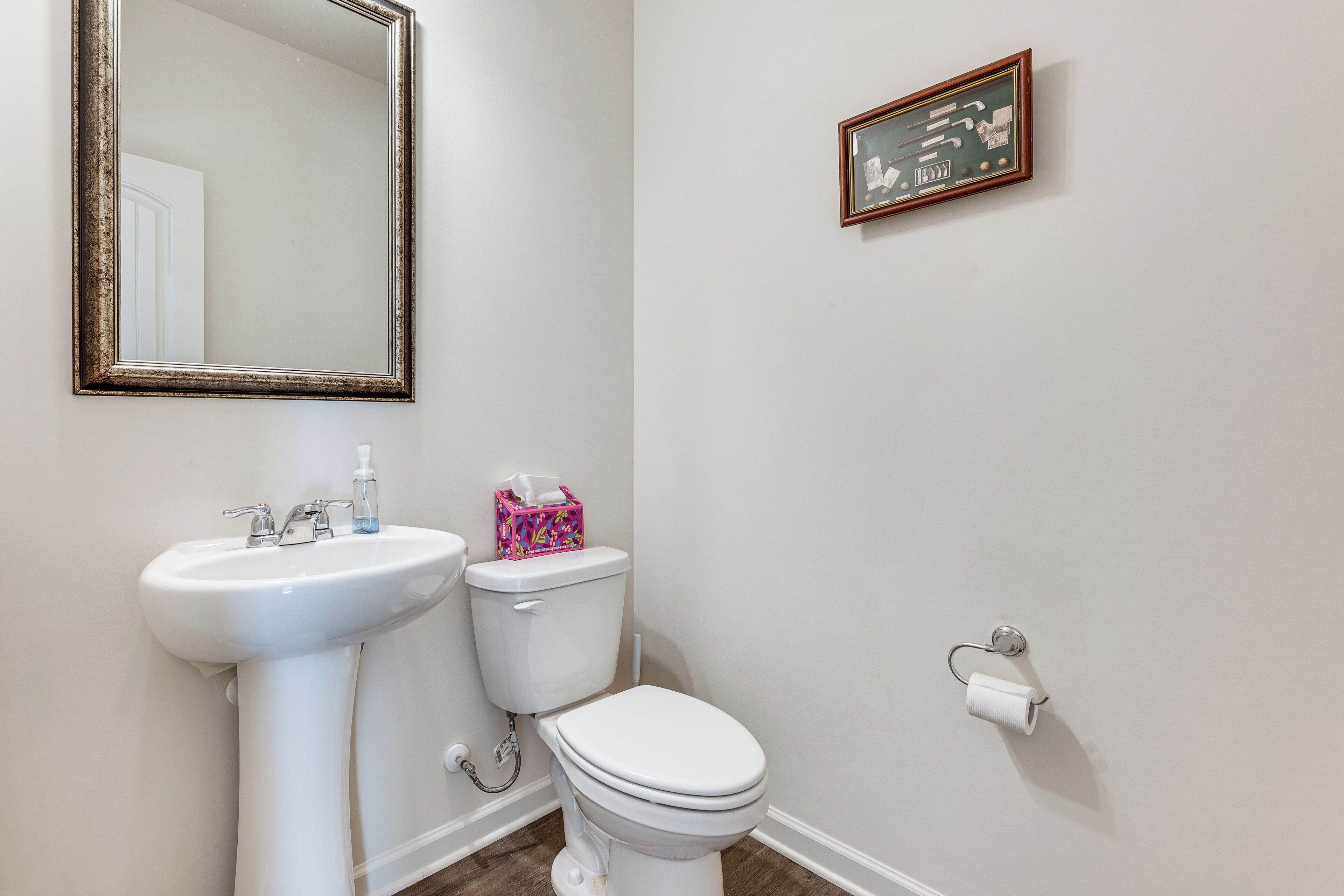 A bathroom with a white sink, toilet, and a mirror.