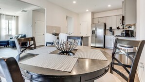 A modern kitchen with stainless steel appliances, a dining area with a round table and chairs, and a living room with a sofa and a coffee table. - Near Atl! Spacious Townhome w/ Patio & WFH Setup (Douglasville)