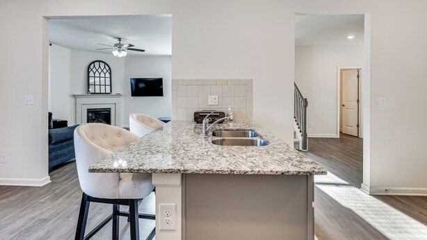A modern kitchen with a granite countertop, a built-in sink, and a ceiling fan. - Near Atl! Spacious Townhome w/ Patio & WFH Setup (Douglasville)