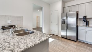 A modern kitchen with granite countertops, stainless steel appliances, and white cabinetry. - Near Atl! Spacious Townhome w/ Patio & WFH Setup (Douglasville)