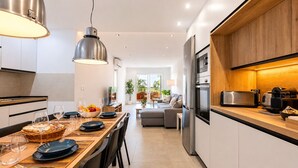 Una cucina moderna con zona pranzo, elettrodomestici in acciaio inossidabile e piano di lavoro in legno.