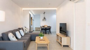 Un soggiorno moderno con un divano grigio, un tavolino in legno e una televisione su un mobiletto in legno.