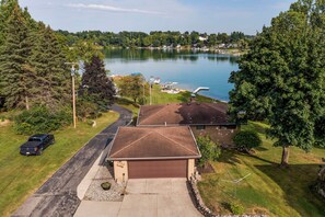 A residential area with a house, a driveway, a garage, and a lake with boats. - Private Beach, 3,000 Sq Ft: Murray Lake Retreat! (Lowell)