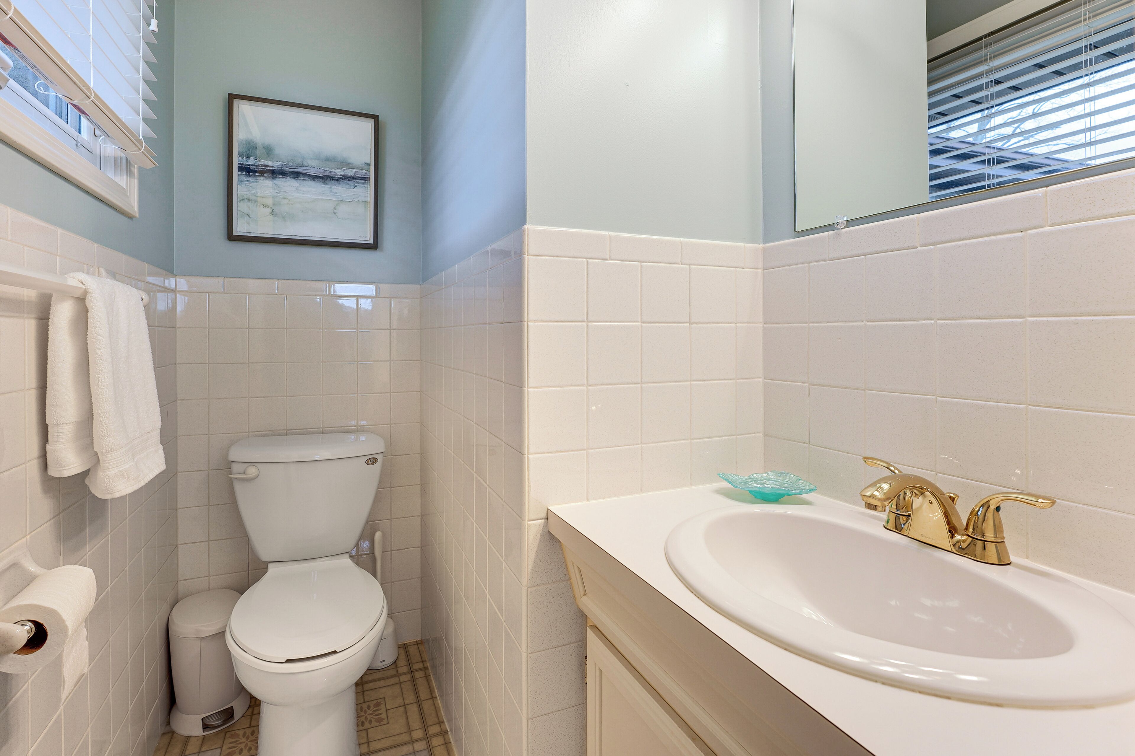 Een badkamer met toilet, wastafel en een foto in een lijst aan de muur.