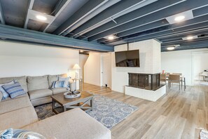 A modern living room with a sectional sofa, a fireplace, and a dining area. - Private Beach, 3,000 Sq Ft: Murray Lake Retreat! (Lowell)