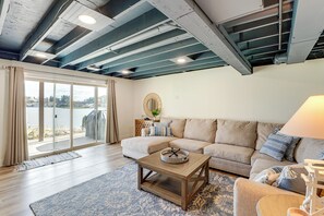 A living room with a sectional sofa, a coffee table, and a large window with curtains. - Private Beach, 3,000 Sq Ft: Murray Lake Retreat! (Lowell)