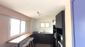 Una cocina compacta con ventana, un lavamanos, una estufa y armarios oscuros.