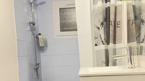 A bathroom with a shower, a sink, and a window.