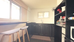 A kitchen with a stove, sink, and bar stools.