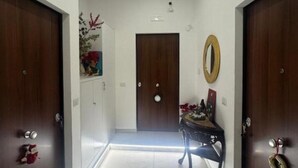 A hallway with two wooden doors, a small table with a mirror, and a decorative plant. - Casa Tecla - Your cozy retreat in the heart of Naples (Napoli)