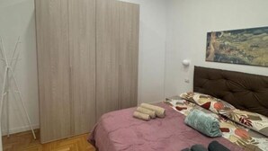 A bedroom with a bed, a wardrobe, a painting on the wall, and a tripod. - Casa Tecla - Your cozy retreat in the heart of Naples (Napoli)