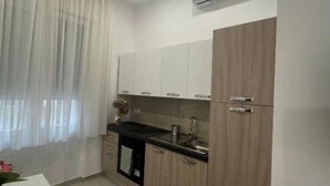 A modern kitchen with light wood cabinets, a black countertop, and a built-in oven. - Casa Tecla - Your cozy retreat in the heart of Naples (Napoli)