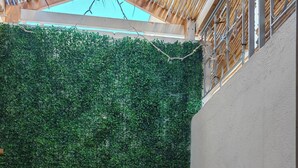 Een houten bank met een bloempot in het midden, een groene wand en een witte wand met een orchidee in een pot.