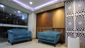 A room with two blue sofas, a wooden panel wall, and a decorative white partition. - Hotel Putra Hills at WTCKL (Kuala Lumpur)