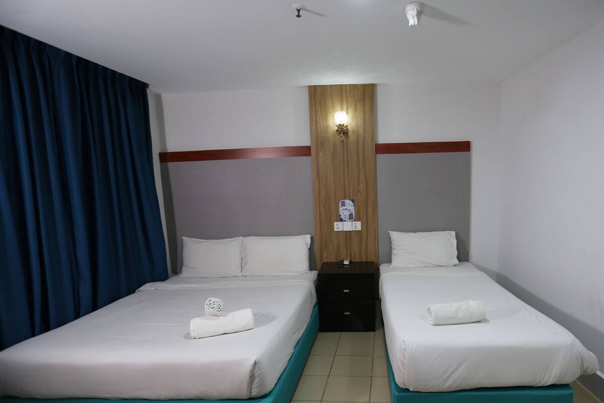 Ein Hotelzimmer mit zwei Einzelbetten, einem Holzkopfteil, einem Nachttisch und einer Wandleuchte.
