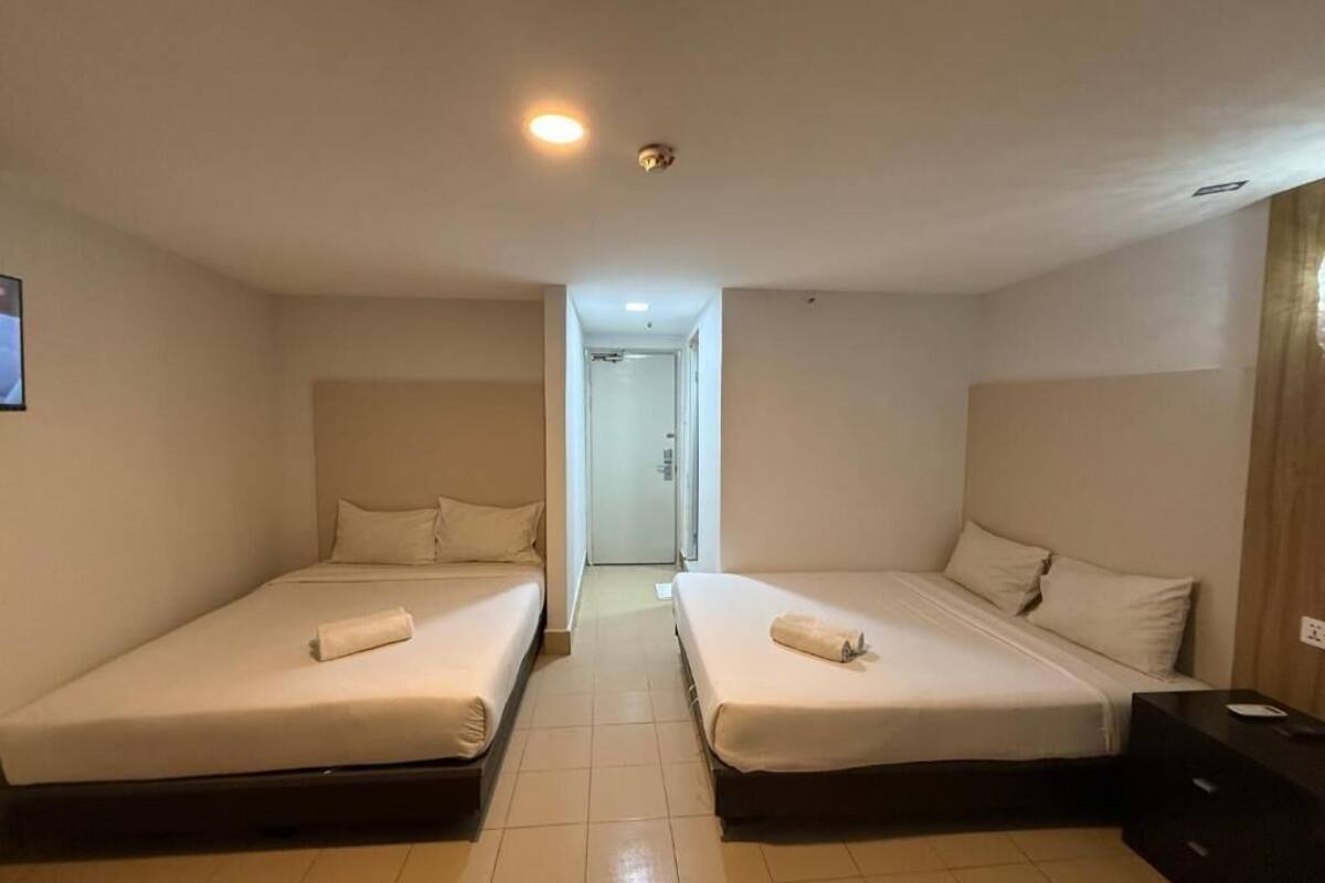 Ein Hotelzimmer mit zwei Einzelbetten, einem kleinen Nachttisch und einem Beistelltisch.