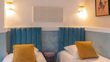 Hotelkamer met twee bedden, elk met een geel kussen, een decoratief paneel en twee wandlampen.