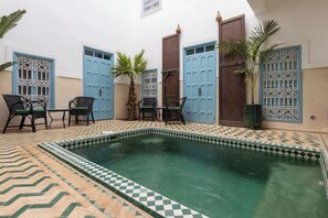A pool area with a checkered floor, blue doors, and outdoor seating. - Palais el Abbassia (Marrakech)
