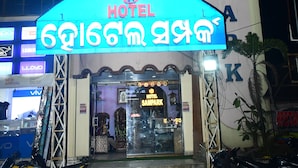Un hôtel avec une enseigne bien visible portant l’inscription « HÔTEL SAMPAK » et un panneau lumineux en langue locale.