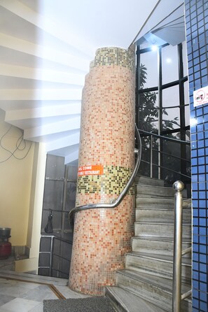 A staircase with mosaic tile walls and metal railings. - Hotel Sampark (Bhadrak)