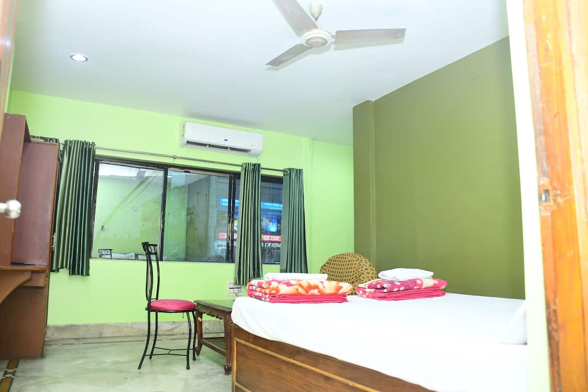 A room with a bed, a desk, a chair, a ceiling fan, and a window with curtains.