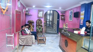 Un espace d’accueil comprenant un comptoir de réception, un escalier et un coin salon où les visiteurs peuvent s’asseoir.