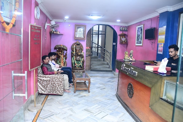 A reception area with a reception desk, a staircase, and a seating area with guests.