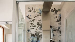 Ein Badezimmer mit Duschkabine aus Glas und floralem Wandpapier.