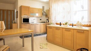 Eine moderne Küche mit Holzausstattung, einem eingebauten Backofen und einem Fenster mit durchsichtigen Vorhängen.