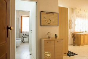 Eine moderne Küche mit Holzschränken, einem gerahmten Kunstwerk an der Wand und einem Fenster mit transparenten Vorhängen.