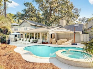 Ein Garten mit Swimmingpool, Gartenmöbeln und einer überdachten Terrasse.