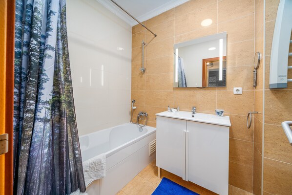 A bathroom with a bathtub, a sink, a mirror, and a shower.
