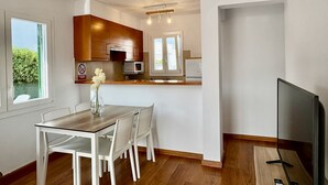 Een moderne keuken met houten kastjes, een magnetron en een eethoek met een tafel en stoelen.
