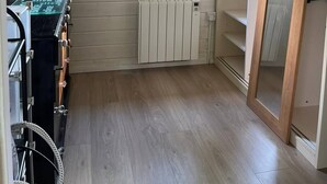 Pieni huone, jossa on puinen katto, ikkuna verhoilla, patteri ja pyörä nurkassa.