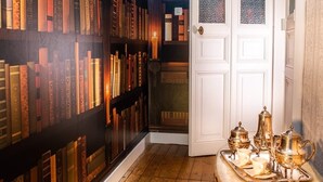 A room with wooden flooring, a white door, and a bookshelf filled with books. - Le Château des Tourelles en Vendée (La Gaubretière)