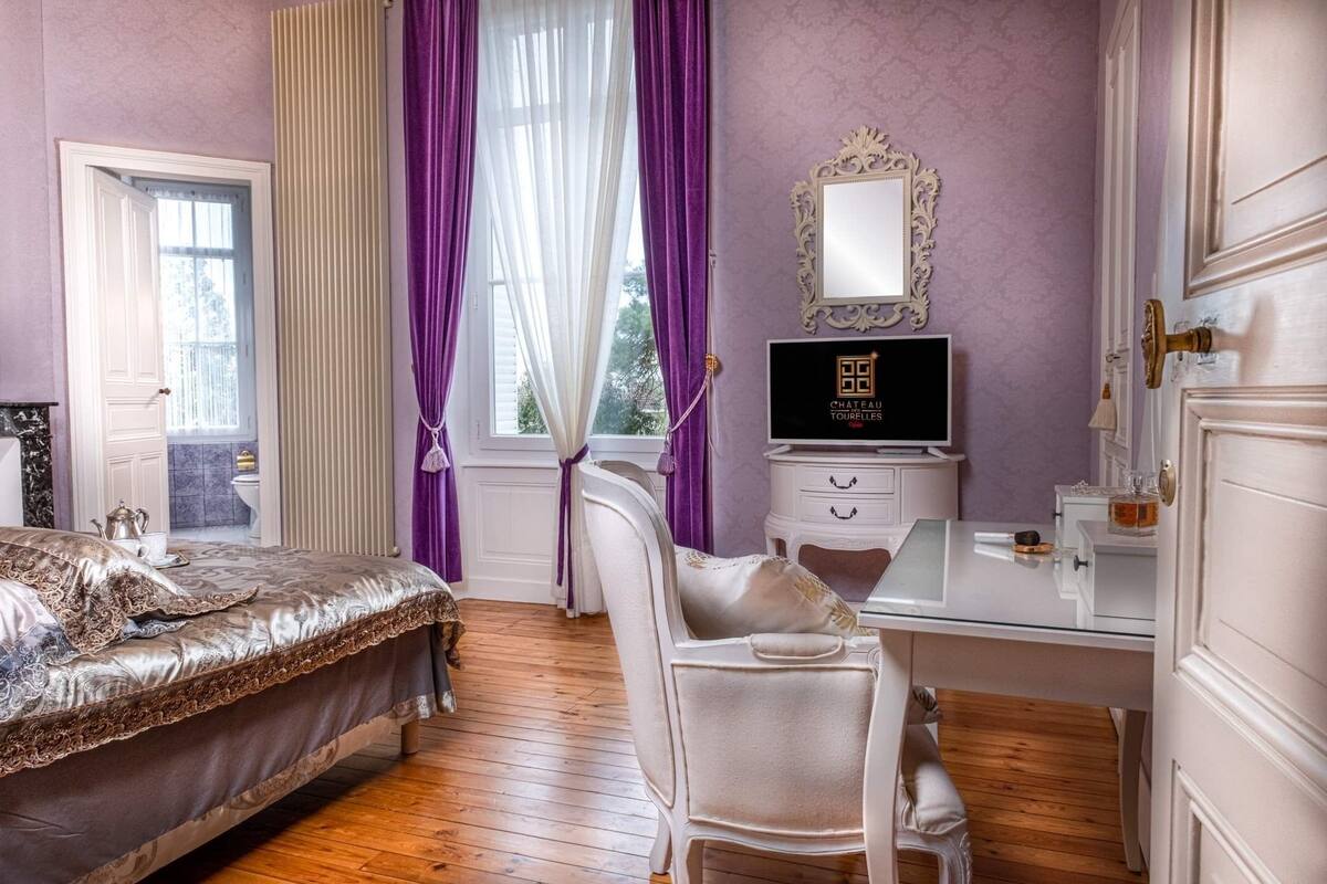 Une chambre à coucher comprenant un lit, un bureau, une chaise, une commode et un miroir.