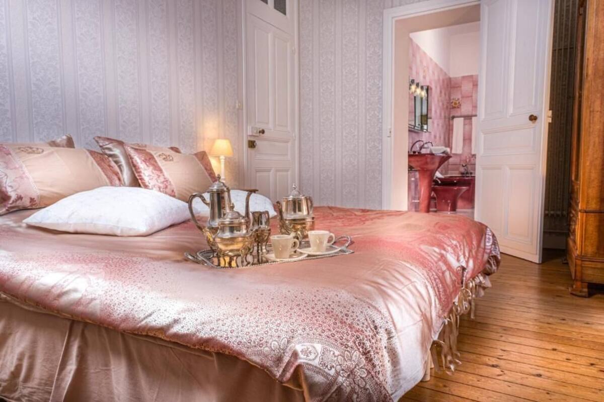 Une chambre à coucher avec un grand lit, une table de chevet avec une lampe et un plateau avec des théières et des tasses.