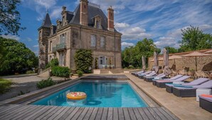 A large stone building with a swimming pool and lounge area. - Le Château des Tourelles en Vendée (La Gaubretière)
