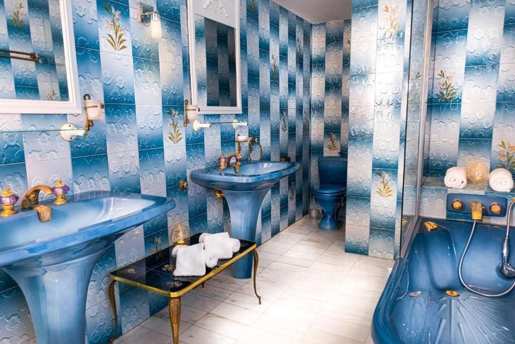 Un baño con baldosas azules estampadas, un lavamanos grande, un bidé y una bañera.