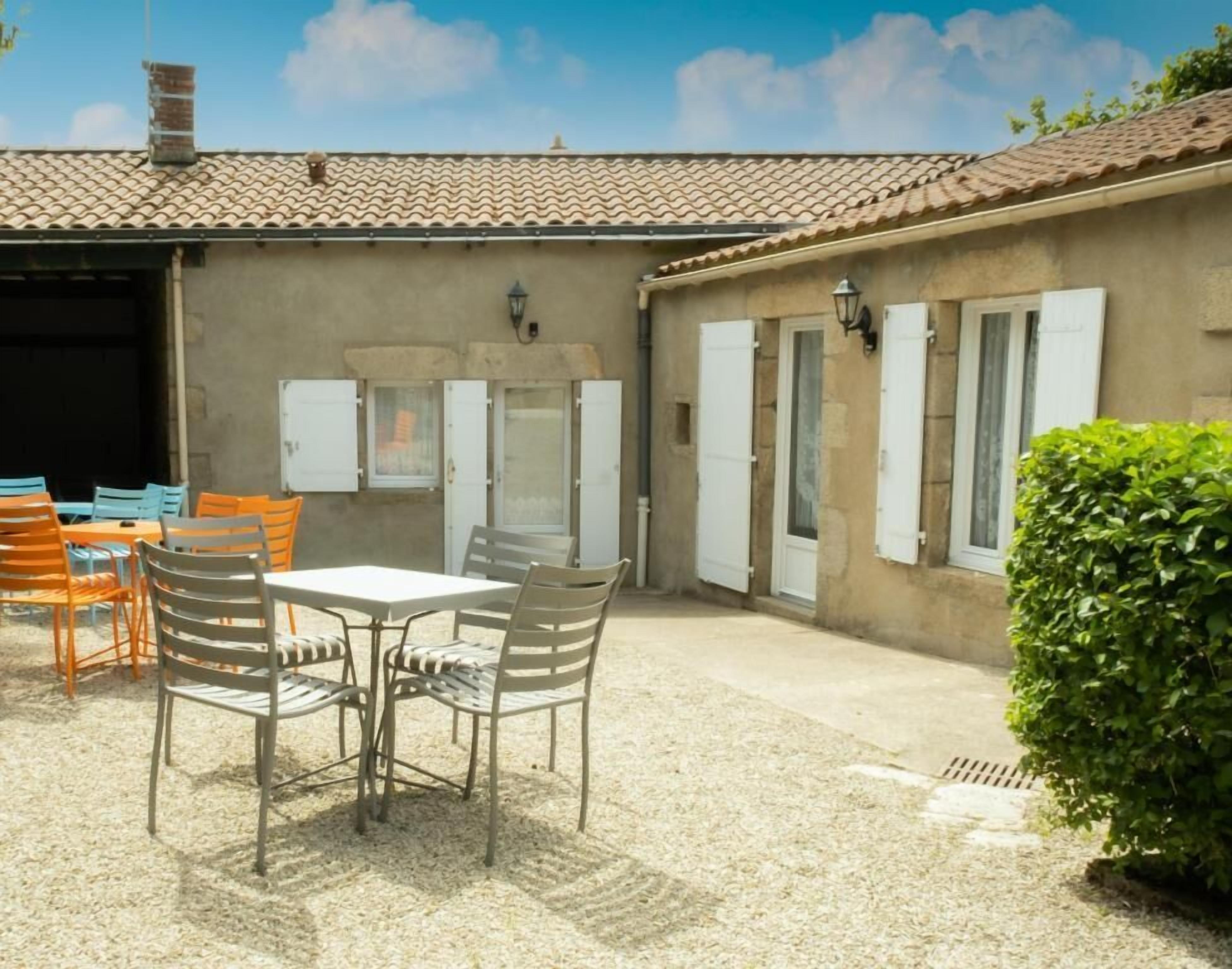 Eine Terrasse mit Tisch und Stühlen, eine überdachte Garage und ein kleiner Garten.