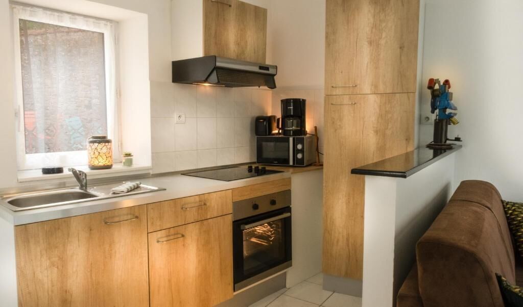 Una cocina moderna con armarios de madera, horno empotrado, microondas y cafetera.