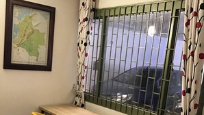 A small room with a wooden table and two yellow chairs, a map on the wall, and a window with metal bars. - Studio Apartament 1st Floor Piedrapintada Coffee Wifi TV (Ibagué)