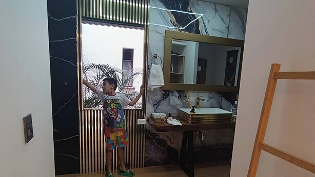 Un baño con pared de mármol, un lavabo y un espejo.